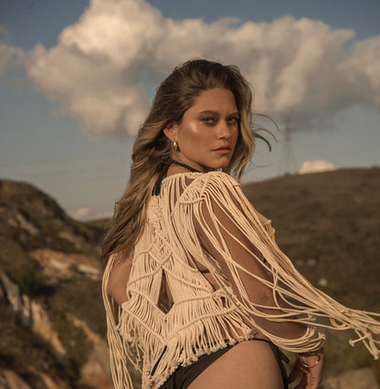 Mujer con chaqueta de macramé ANASTASI en entorno natural, estilo boho sofisticado, al atardecer.