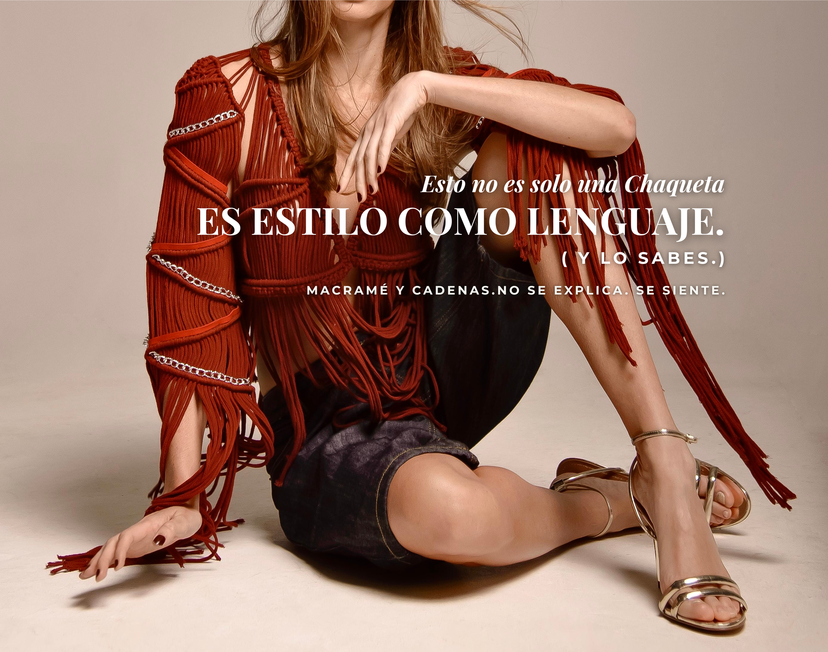 Mujer sentada usando chaqueta artesanal en macramé rojo vino con cadenas metálicas y detalles de gamuza en mangas y pecho. Diseño estructurado de Anastasi.