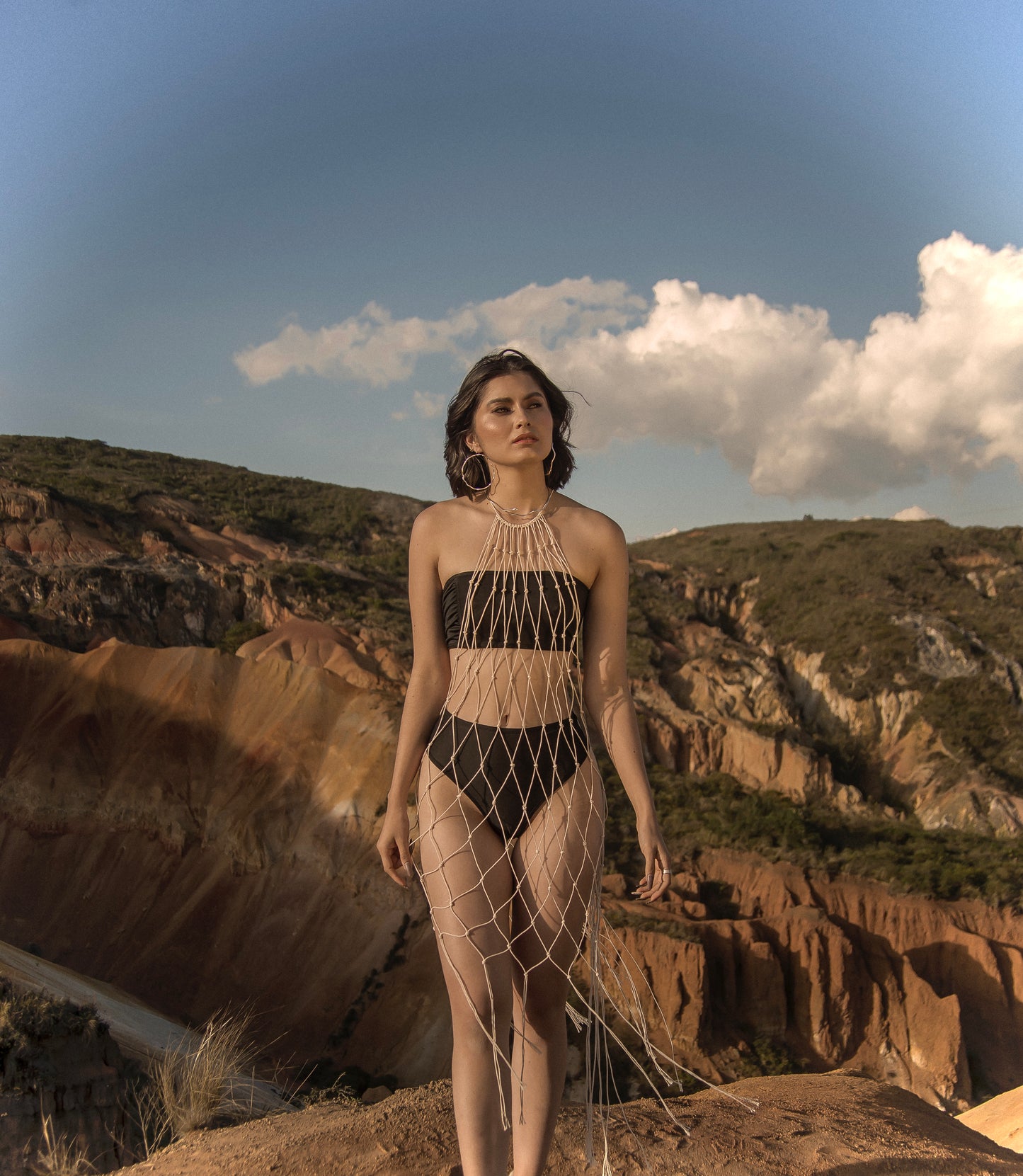 Mujer de pie en montaña usando Malla Morocco en macramé artesanal. Cover‑up de algodón tejido a mano por ANASTASI. Estilo con estructura.