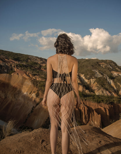 Espalda de mujer usando la Malla Morocco de macramé crudo en paisaje árido. Diseño ANASTASI con intención artesanal y silueta fluida.